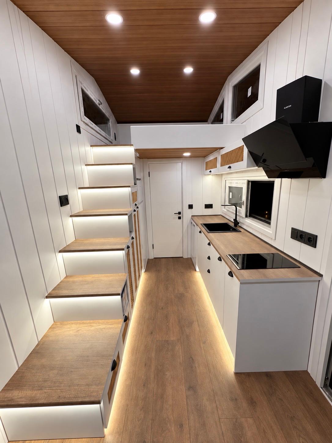 Küchenzeile und beleuchtete Treppe zum Loft im Pera Rustik mit weißen Wänden und Holzdecke